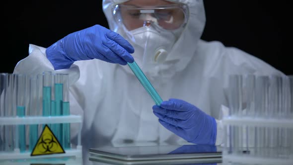 Female Toxic Lab Worker Making Notes on Tablet Analyzing Biohazard Fluids, Crime