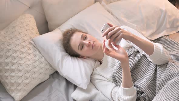 Top View of Young Girl Using Smartphone in Bed Browsing
