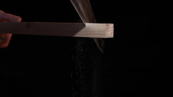 Man Carpenter Saws a Wooden Board with a Hand Saw