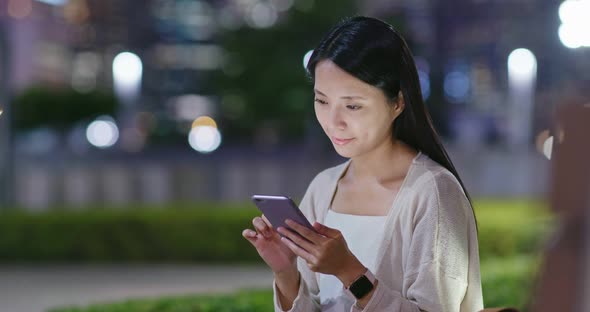 Woman look at mobile phone in city at night