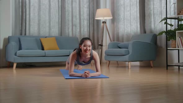 Trainer Female Speaking And Doing Yoga In Forearm Plank Pose While Teaching Exercise At Home