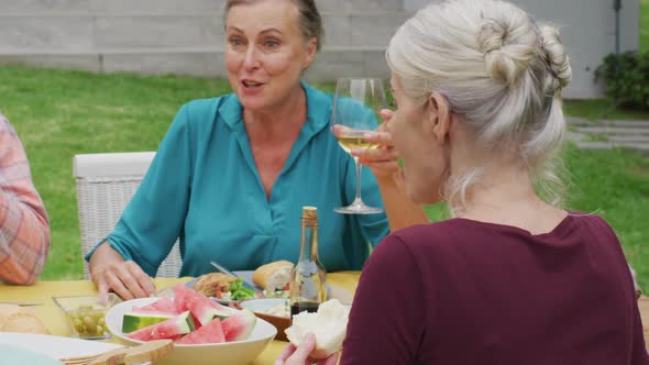 Animation of happy caucasian senior woman eating lunch in garden with friends