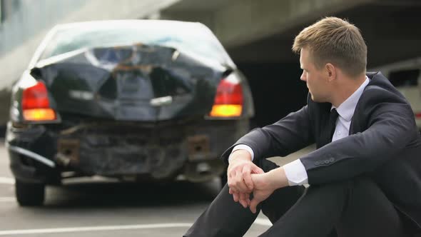 Upset Man Sitting on Road After Car Crash, Waiting Police, Lack of Experience