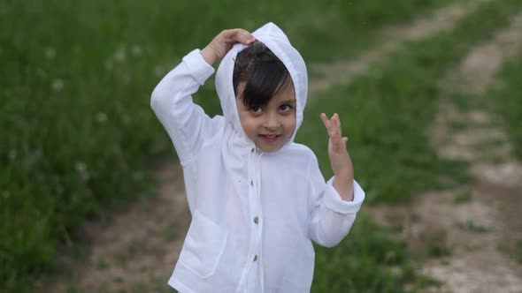 Caucasian Child Boy in a White Sweater with a Hood Dancing on the Road