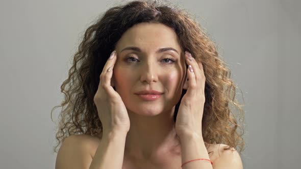 Beautiful Middleaged Woman Massages Her Face with Light Movements