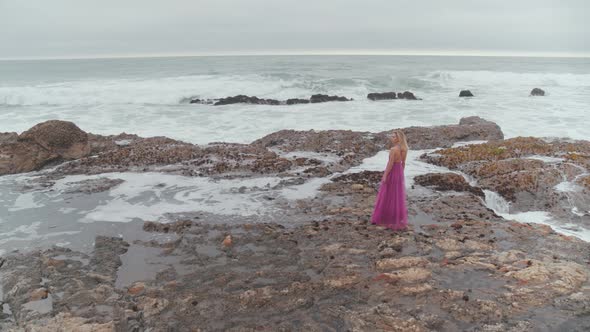Woman Standing On The Rocky Shore