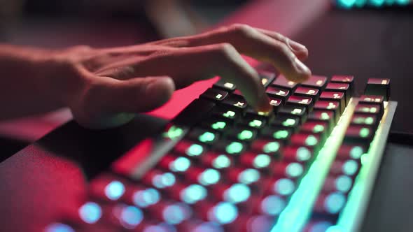 Young Gamer Plays a Video Game Closeup of Hands Player Uses Gaming Keyboard Illuminated Coral Color