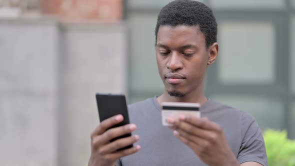 Portrait of Young African Man Making Online Payment on Smartphone