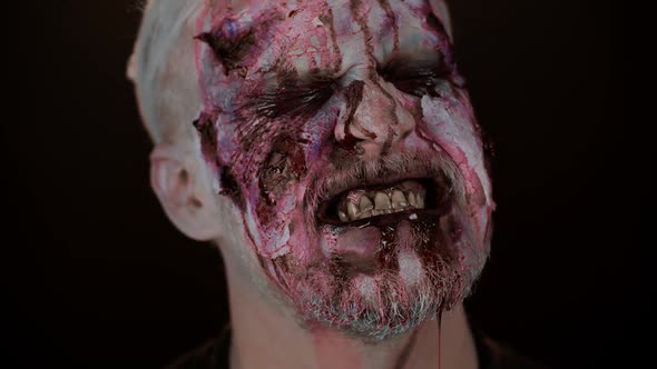 Frightening Man Face with Halloween Zombie Bloody Wounded Makeup Blood Flows and Drips on Face