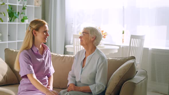 Young daughter telling mom gossip on sofa