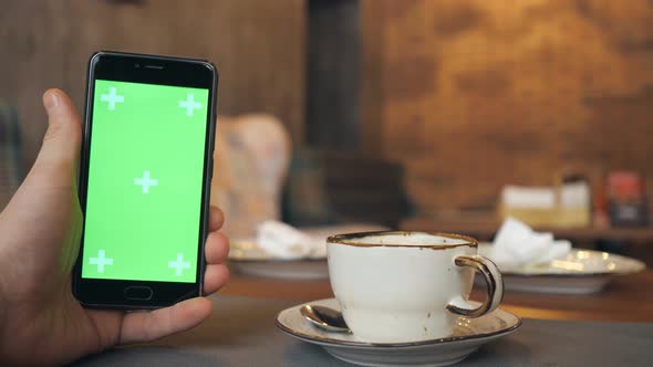 Human Hands Is Holding Smartphone with Green Screen in Cafe