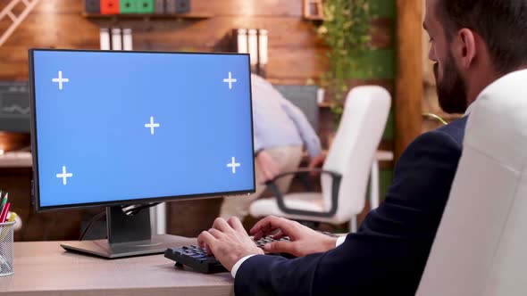 Back View of Businessman in His Office Typing on Computer Screen with Mock-up