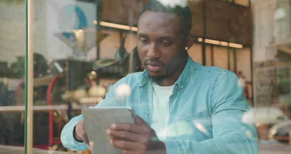 Black-Skinned Man with Stylish Beard which Sitting Near the Window of Street Cafe