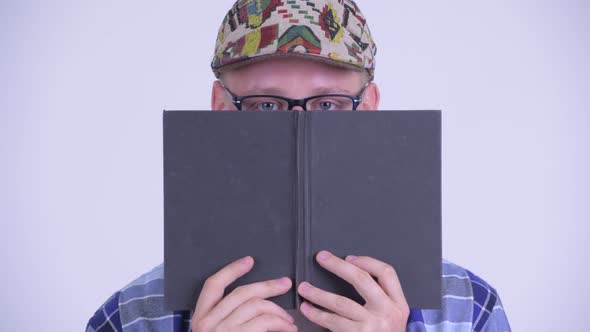 Face of Young Hipster Man Thinking While Covering Face with Book