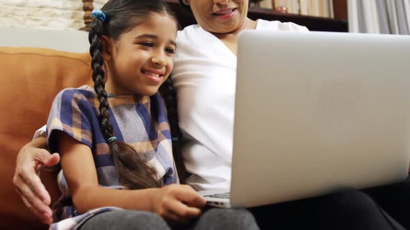 Grandmother and granddaughter using laptop in living room 4k