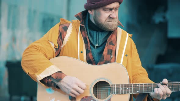 A Poor Man is Playing the Guitar in the Street