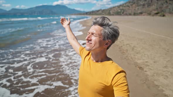 Close Up Selfie Portrait of Happy Middle Aged Greyhead Man at Sea Coast Enjoys Sunny Day on