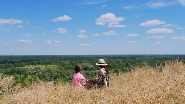 Beautiful Summer Landscape. Woman and Little Girl, Mom and Daughter, Sit on Cliff Edge, Talking and