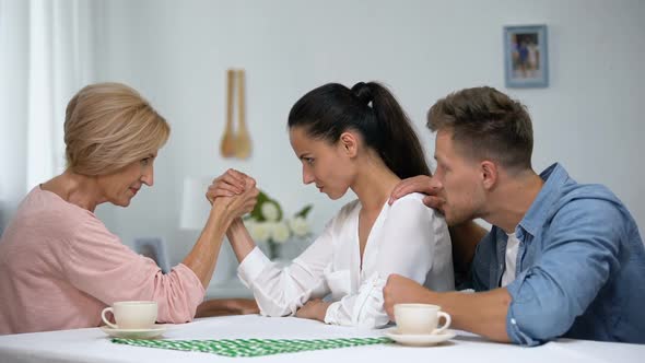 Man Supporting Wife During Arm Wrestling Competition With Mother, Family Battle