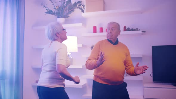 Elderly Man and Woman Dancing Indoors with Disco Lights