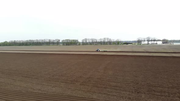 Aero. Spring Sunny Day. On an Agricultural, Farming Field, a Tractor Plows Land, Soil.. Modern