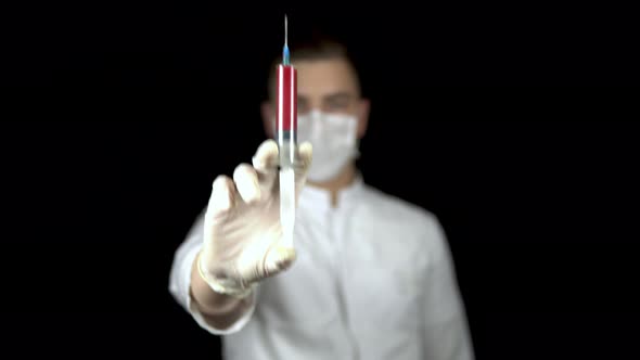 Blood in a Syringe Close-up on a Black Background. A Man Doctor Holds Out a Syringe with Blood To