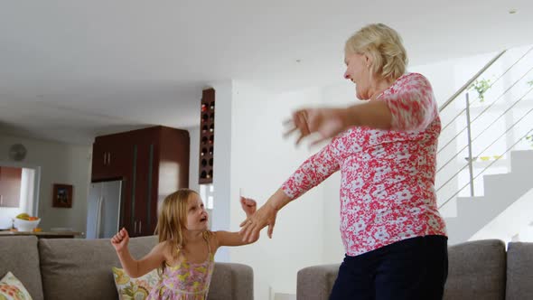 Grandmother and granddaughter dancing in living room 4k