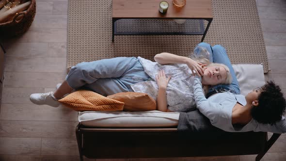 Top Shot of Young Girl Laying on a Lap of Her Girlfriend Sitting on the Couch