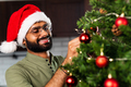 indian man in santa hat decorating Christmas tree with baubles - PhotoDune Item for Sale