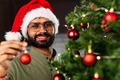 indian man in santa hat decorating Christmas tree with baubles - PhotoDune Item for Sale