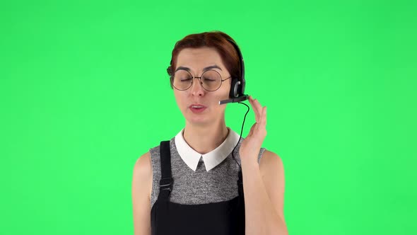 Portrait of Funny Girl in Round Glasses with Headset Helping with Customer Service. Green Screen