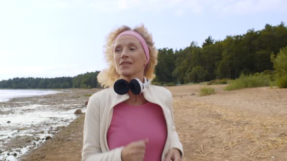 Senior Active Woman Running Along Sea Coast Early in Morning.