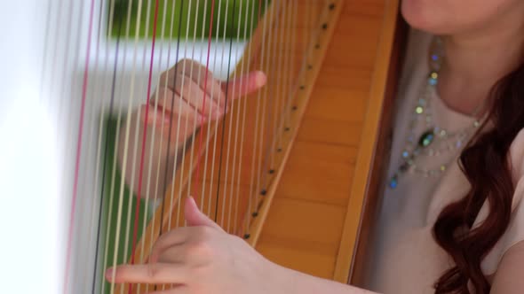 A woman plays a harp in a gazebo in the Park. Hands close up slow motion