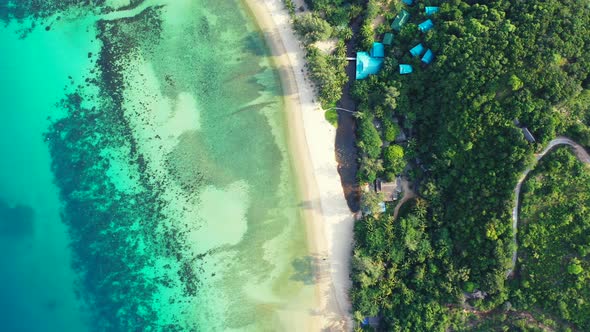 Peaceful white sandy beach washed by colorful pattern of calm lagoon with coral reefs and pebbles se