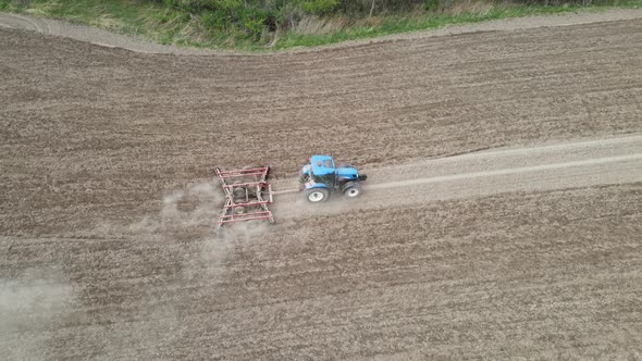 Birds eye view of farmer tilling field in preparation for planting. Blue tractor in the field.