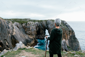 ekking stick exercising near some cliffs. senior person doing sports and contemplating the landscape.