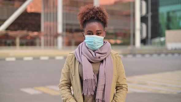 Young attractive black woman putting on medical mask against cityscape