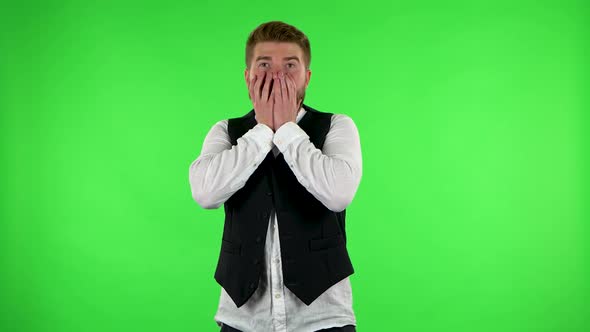 Man Carefully Examines Something Then Fearfully Covers His Face with His Hands. Green Screen