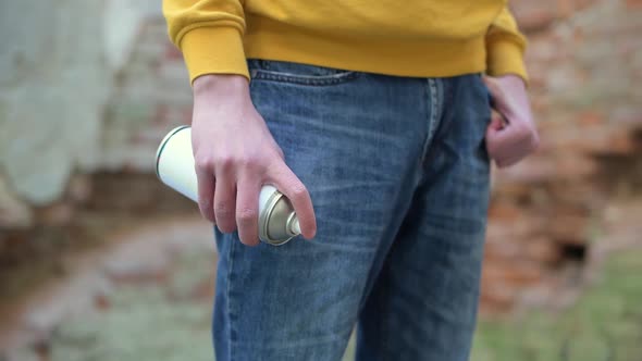 teenager is about to paint a street wall and holds paint in his hand