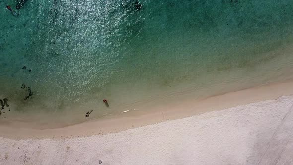 Descending drone shot showing girl relaxing in transparent ocean water in summer