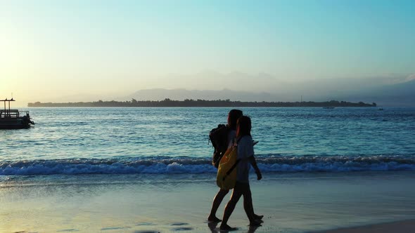 Modern smiling girls travelling in the sun at the beach on clean white sand and blue background 4K