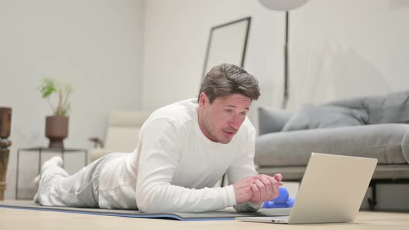 Man Talking on Video Call on Laptop Yoga Mat at Home