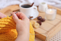hands of a woman knitting sweater with yellow soft wool. coffee and snacks on a wooden tray - PhotoDune Item for Sale