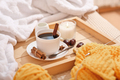 Cup of coffee with cinnamon and candle on rustic wooden serving tray in cozy bed with blanket.  - PhotoDune Item for Sale