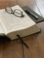 An Open Bible Sits and a Pair of Reading Glasses sit atop an Old Weathered Wooden Table - PhotoDune Item for Sale