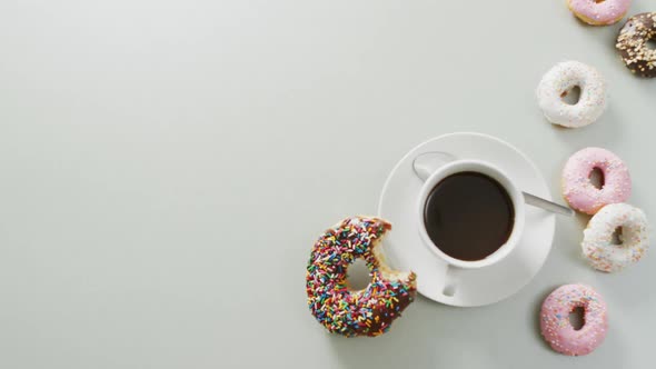 Video of donuts with icing and cup of coffee on white background