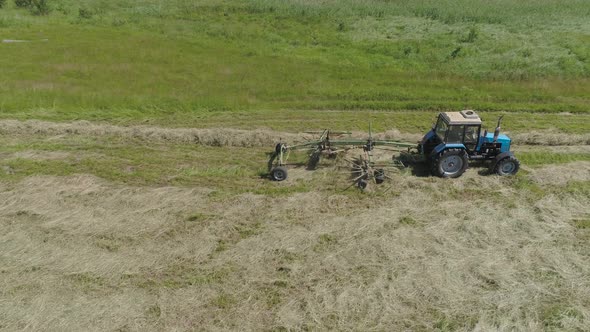 Tractor with Rake Tedders on the Farm Field