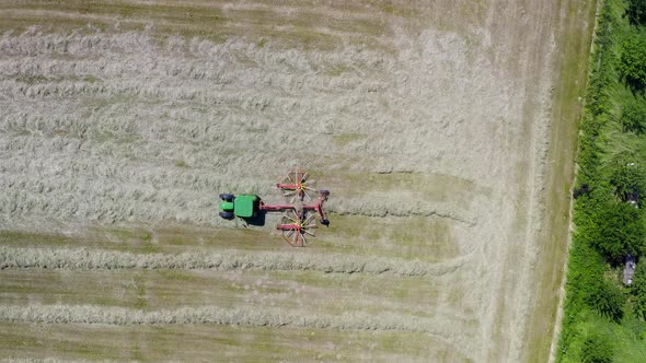 Farmland working - a tractor with its twin rotor rake is cleaning up the field, filmed as top down s
