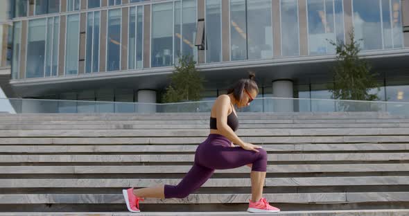 Happy Mixedrace Woman in Sportswear Does Exercises on City Stairs