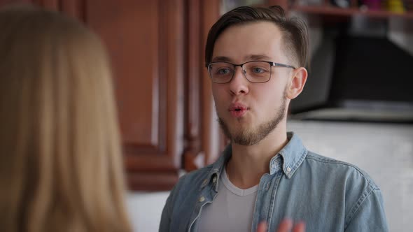 Portrait of Excited Smiling Handsome Man in Eyeglasses Talking with Woman in Kitchen at Home